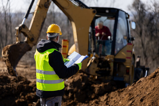 Construction workers coordinating plant and labour on a live site
